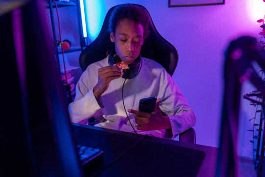 Teen Gamer Eating Snack While Using Smartphone