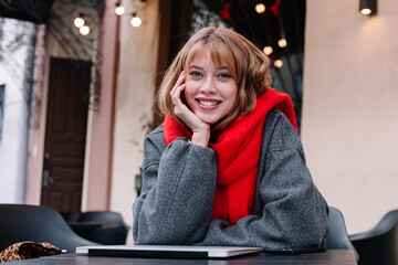 Young woman wearing a red scarf enjoys a cozy moment at a cafe