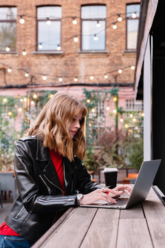 A woman working on a laptop at a cozy cafe with string lights