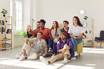 Portrait of excited young diverse group of friends watching sport football match on tv supporting...