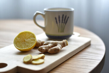 Cup of tea and ginger and lemon on wooden cutting board