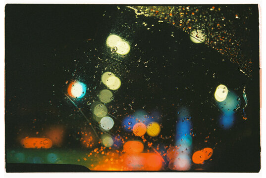 Nighttime city lights blurred by raindrops on a car window