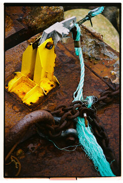 Rusty metal dock fixture with chain and rope near water