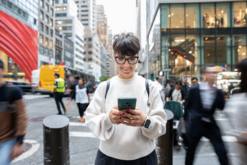Smiling tourist using smartphone in busy manhattan street