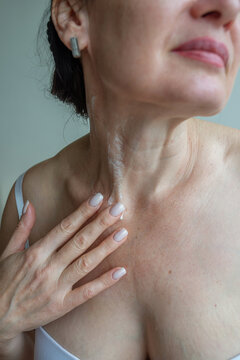 Portrait of mature woman applying cream on her neck