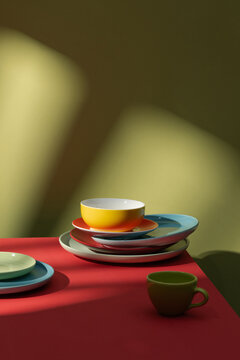 Colorful Stacked Plates and Bowls on Red Table with Green Background