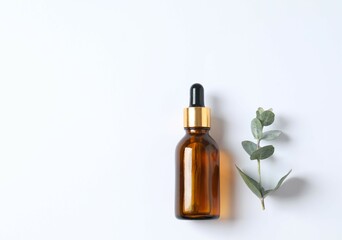 Eucalyptus essential oil in a glass bottle with green eucalyptus leaves on a white background. Aromatherapy concept. Spa. Natural organic ingredients for cosmetics and body care.