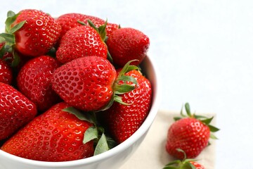 Delicious fresh red strawberries in a bowl on a gray background