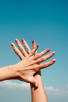 Hand manicure with colorful nails over blue sky