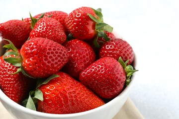 Delicious fresh red strawberries in a bowl on a gray background