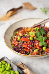 Healthy Asian style quinoa bowl with tomatoes, cherry, carrot and soy sauce dressing. close-up.