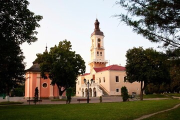 Fototapeta premium Ancient building of the town hall with a clock tower and a historic chapel on the central square of the city on a sunny day. An architectural ensemble with elements of baroque and classicism, surround