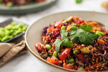 Healthy Asian style quinoa bowl with tomatoes, cherry, carrot and soy sauce dressing.