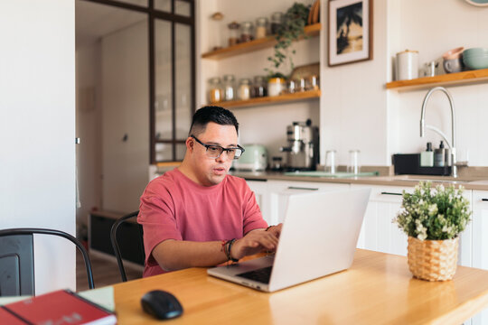Man with Down syndrome working on laptop in kitchen