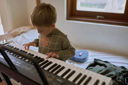 A boy playing on a synthesizer at home