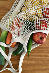 Vertical photo of reusable mesh bag with vegetables and fruits