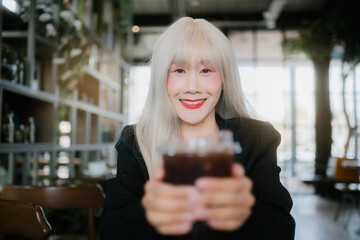 smiling woman with long white hair holds drink in e