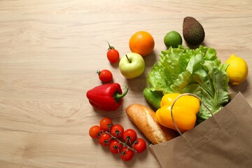 Paper bag, vegetables and fruits on wooden background, space for text