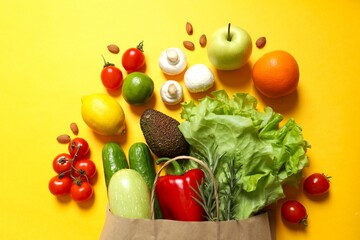 Paper bag, vegetables and fruits on color background, space for text