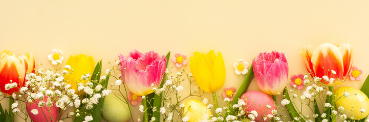 Spring Easter background, multi-colored Easter eggs with tulips and gypsophila on a yellow...