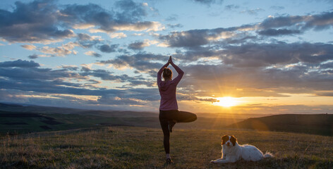 woman with white dog doing yoga at sunset