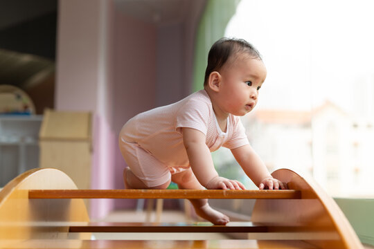 Adorable Baby Crawling on Wooden Climbing Structure Indoors
