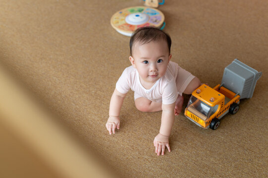 Cute Baby Playing on Carpet with Toy Truck and Curious Look