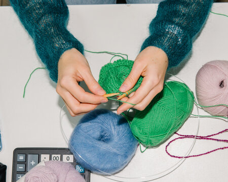 The girl knits at her desk.