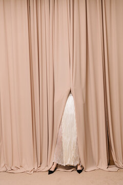 Elegant Mystery Woman Behind Beige Curtains in Stylish Dress