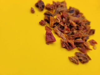 Little portion of red paprika on a yellow background.