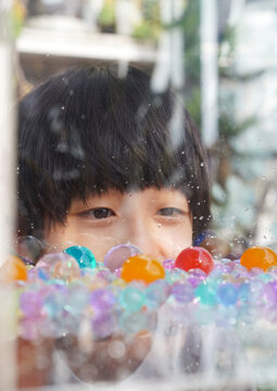 An Asian boy playing with colored glass balls at home