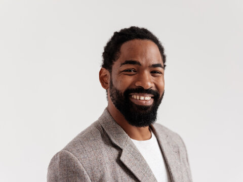 Smiling Man in Casual Blazer Against a Plain Background