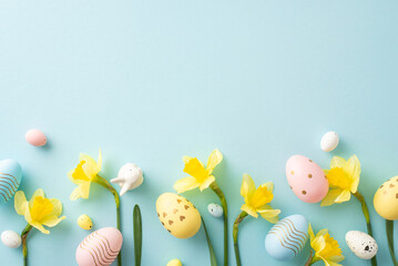 Festive composition featuring colorful Easter eggs with daffodil flowers arranged on a soft blue backdrop, symbolizing springtime and celebration