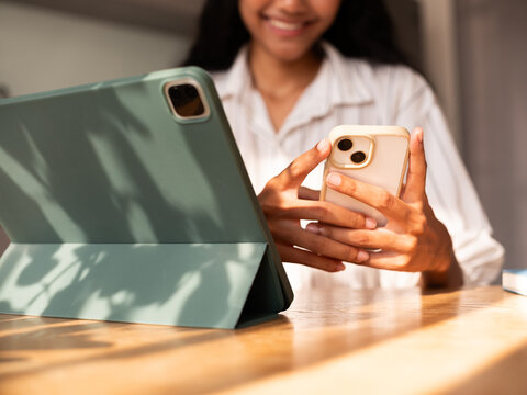Woman Smiling While Using Smartphone and Tablet at Home