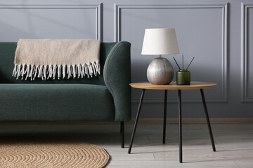 Comfortable sofa and side table near grey wall in room