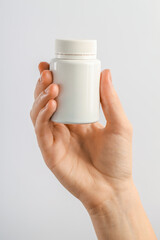 Woman holding medical bottle with pills on white background, closeup