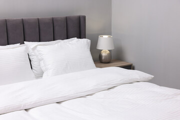 Bed with clean linens and pillows indoors