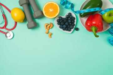 Healthy lifestyle and balanced eating background with  vegetables, fruits, blueberries, medical stethoscope and dumbbells