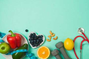 Healthy lifestyle and balanced eating border frame with  vegetables, fruits, blueberries, medical stethoscope and dumbbells