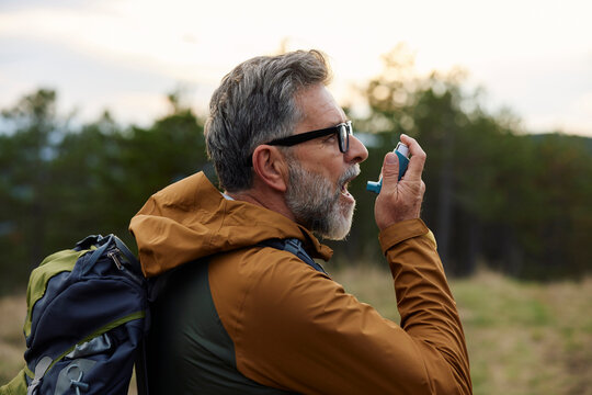 Asthmatic takes a dose of an inhaler on a mountain