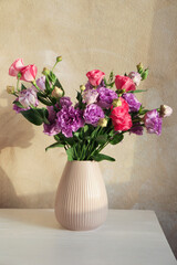 Vase with beautiful eustoma flowers on white wooden table