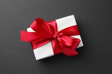 Gift box with red bow on black background, top view