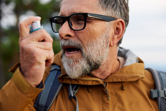 Man takes a dose of an inhaler on a mountain
