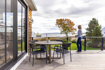 Exterior porch view of fall foliage with woman drink coffee 