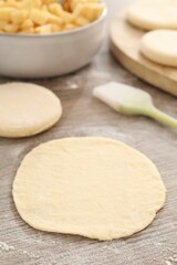 Making pirozhki (stuffed pastry pies). Pieces of dough on wooden table, closeup