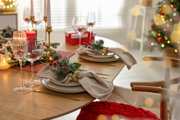 Christmas celebration. Festive table setting with dishware, glasses and decor in room