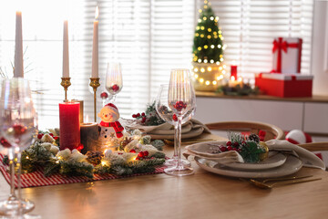 Christmas place setting with festive decor on wooden table in room
