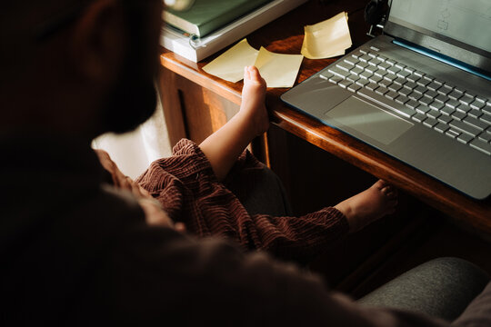 Anonymous man woking on laptop with a baby on his lap