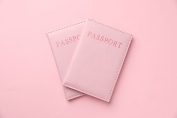 Passports in color covers on pink background, top view