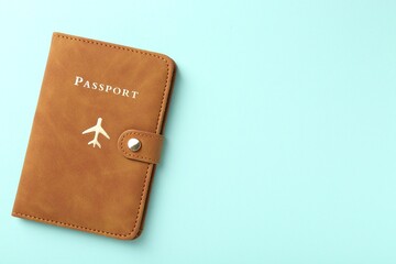 Passport in brown cover on turquoise background, top view. Space for text